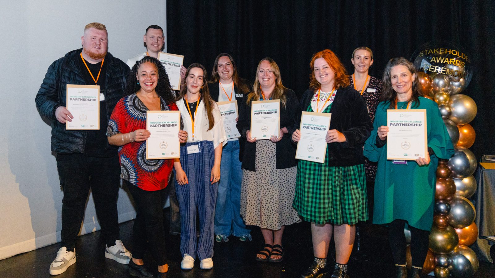 Young people holding award certificates at an event at The Manchester College 2024.